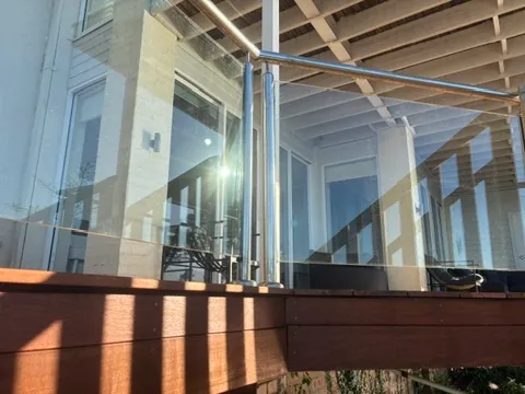 A custom frameless glass balustrade with stainless steel posts on a timber deck