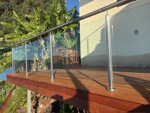 A merbau deck edge showing a clean timber fascia beneath a glass and stainless balustrade