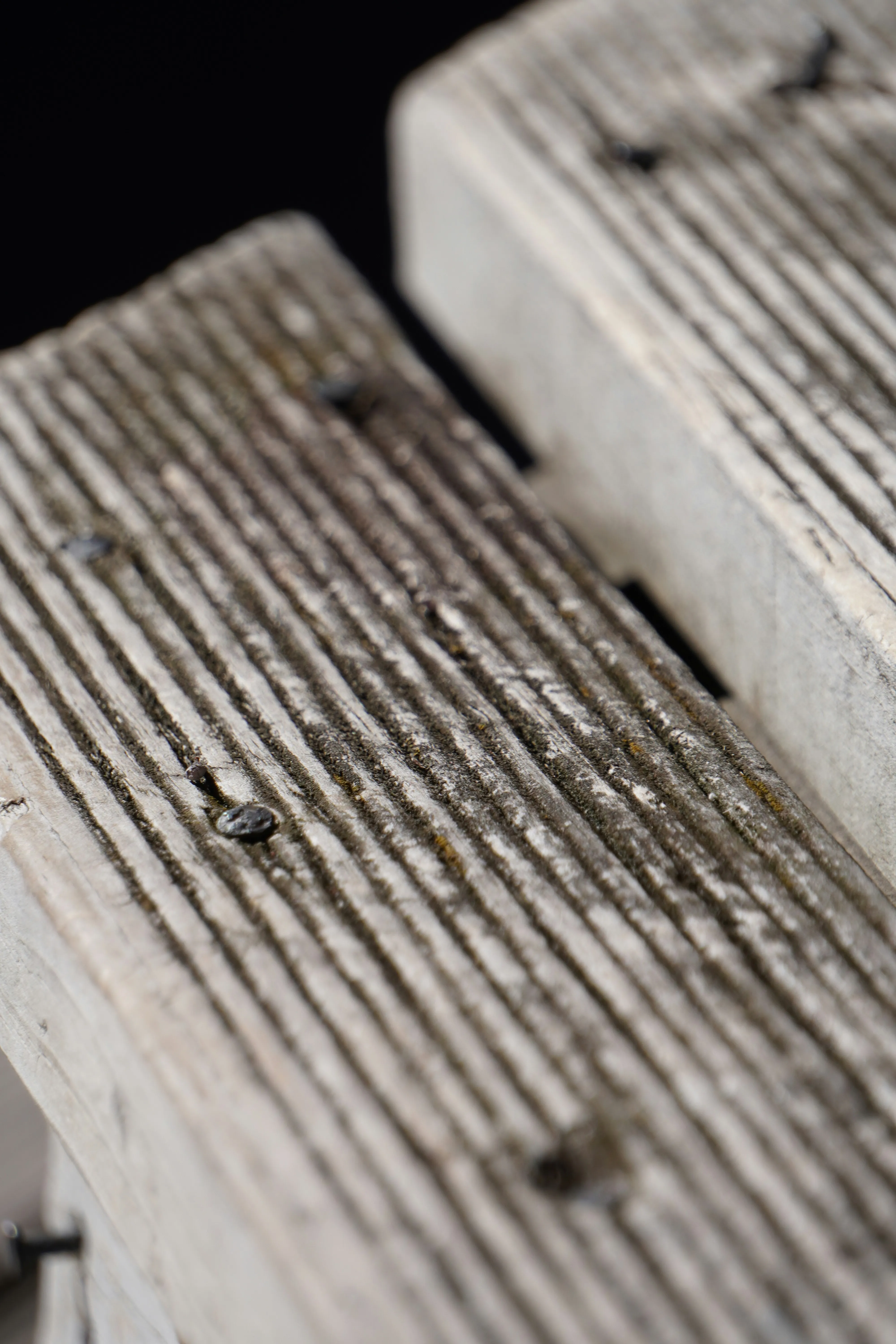 A hardwood deck being re-oiled during restoration, freshly oiled boards beside dry ones
