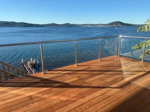 A finished merbau hardwood deck with a glass balustrade overlooking the water